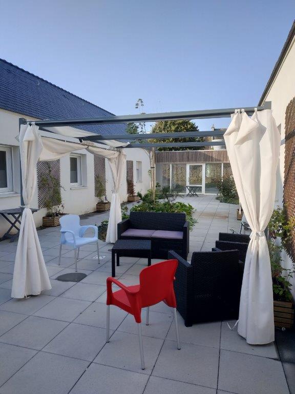 Terrasse du patio avec salons de jardin et pergola aux rideaux blancs